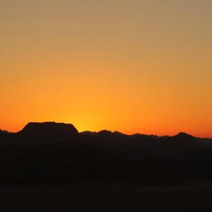 a sunset over the mountains in the desert at Wadi Rum Originality Camp in Wadi Rum