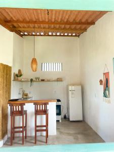 cocina con mesa, sillas y nevera en Caiana loft Cumuruxatiba en Cumuruxatiba