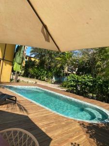 a swimming pool with an umbrella on a wooden deck at Pousada Bambu Dourado in Marau