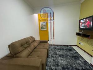 uma sala de estar com um sofá e uma televisão de ecrã plano em Apto Conquista Imóveis exclusivo para Booking em Vitória da Conquista