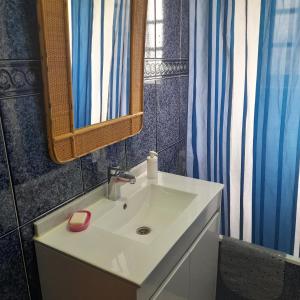 ein Badezimmer mit einem weißen Waschbecken und einem Spiegel in der Unterkunft Quarto duplo em Foros de Salvaterra in Estanqueiro