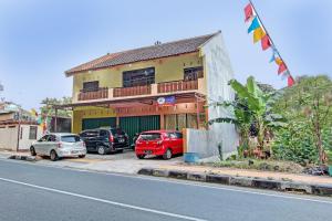 a building with cars parked in a parking lot at SPOT ON 93007 Guest House Lestari in Prambanan