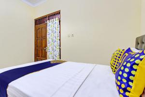a bedroom with a bed and a wooden door at SPOT ON 93007 Guest House Lestari in Prambanan