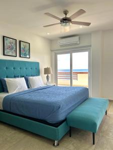 a bedroom with a blue bed and a large window at Condominio frente al mar Roatán in Roatán