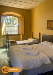 2 camas en una habitación con ventana en Brumas Ouro Preto Hostel e Pousada, en Ouro Preto