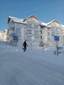 a person standing in the snow in front of a building at Apartament Czarna Góra in Sienna