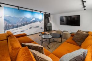 un soggiorno con divano arancione e TV di Tatry Mozaika Willa PREMIUM & Sauna, Jacuzzi, Flipper by RentiloPL a Zakopane