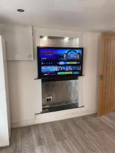a flat screen tv above a fireplace in a living room at 1 Bedroom Apartment by London Stratford in London