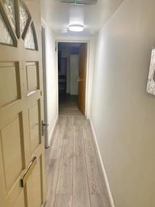 an empty hallway with a door and a wooden floor at 1 Bedroom Apartment by London Stratford in London
