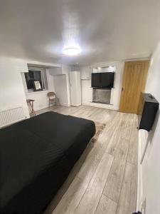 a bedroom with a black bed and a wooden floor at 1 Bedroom Apartment by London Stratford in London