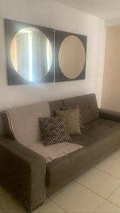 Un sofá con dos espejos en la pared y un espejo encima. en Apartamento Orla do Cabo Branco, en João Pessoa