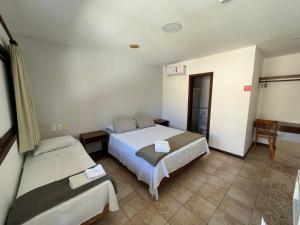 Un dormitorio con 2 camas y una silla. en Pousada Maristella en Salvador