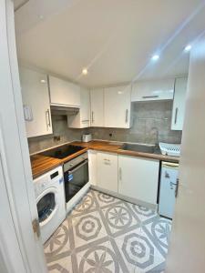 a kitchen with white cabinets and a sink and a dishwasher at 1 Bedroom Apartment by London Stratford in London