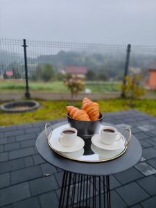 una mesa con un bol de cruasanes y tazas de café en CHWILO TRWAJ - dom z kominkiem i pięknym widokiem na góry, en Korbielów