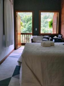 a bedroom with a large bed with two windows at Pousada Sítio das Pedras in Domingos Martins