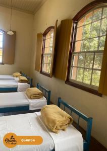 a row of beds in a room with windows at Brumas Ouro Preto Hostel e Pousada in Ouro Preto
