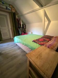 Un dormitorio con una cama verde y una mesa en Maison de 3 chambres avec jardin clos et wifi a Dreux, en Dreux
