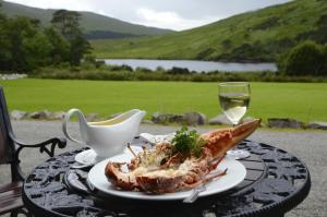 a table with a plate of food and a glass of wine at Delphi Lodge in Leenaun