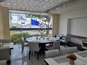 ein Esszimmer mit einem Tisch und Stühlen sowie einem großen Fenster in der Unterkunft Tropical Barra Hotel in Rio de Janeiro