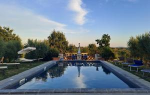 a large swimming pool in a yard with chairs and trees at Cortona Holiday Home in Cortona