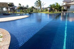 uma piscina com água azul num resort em Flat amplo em condominio beira mar em São Miguel do Gostoso