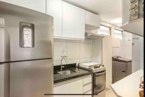 uma cozinha com armários brancos e um frigorífico de aço inoxidável em Coração de Boa Viagem em Recife