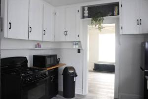 een keuken met witte kasten, een fornuis en een vuilnisbak bij Comfy! Cozy! Spacious! in Eastpointe