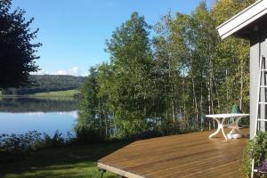 a wooden deck with a table and a view of a lake at Idyllic lakeside cabin (hytte) in Horten