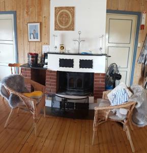 a living room with a fireplace and two chairs at Idyllic lakeside cabin (hytte) in Horten