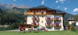 a building with flowers on the balconies of it at Hotel Ortles Dolomiti Walking & Spa in Cogolo