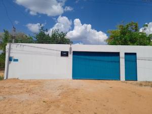 uma cerca branca com portas azuis numa estrada de terra em Rancho peixe grande em Sao Miguel do Araguaia