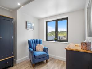 um quarto com uma cadeira azul e uma janela em Cleggan Pierside Apt 1 em Cleggan