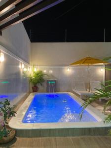 a large blue swimming pool with an umbrella at Casa Brisas Arembepe - arejada e aconchegante - litoral norte da Bahia com crianca - WiFi in Arembepe