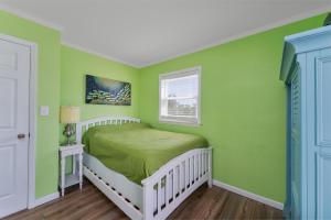 a green bedroom with a bed and a window at 7039 - A Wave From It All by Resort Realty in Rodanthe
