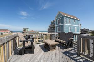 a deck with two chairs and a table and a house at 7039 - A Wave From It All by Resort Realty in Rodanthe
