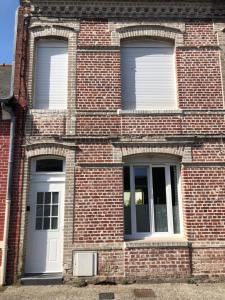 un edificio de ladrillo con dos ventanas y una puerta blanca en Maison tout confort, en Corbie