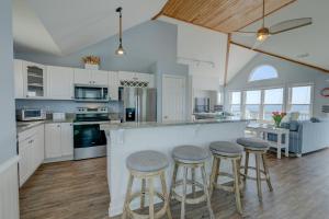 a kitchen with white cabinets and bar stools at 7048 - Tide Song by Resort Realty in Rodanthe