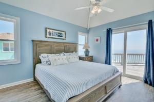 a bedroom with a bed with blue walls and windows at 7048 - Tide Song by Resort Realty in Rodanthe
