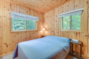 a bedroom with a bed and two windows at Detroit Lakes Cabin Rental on Long Lake! in Detroit Lakes