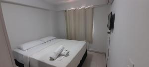 Dormitorio pequeño con cama blanca y TV en Brisas do Cabo Branco, en João Pessoa
