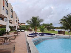 a pool with tables and chairs next to a building at Guarajuba Paraiso dos Coqueiros B02 in Camaçari