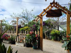een houten pergola met bloemen in een tuin bij Cleverlearn's Homestay & Coffee in Ấp Ða Lợi