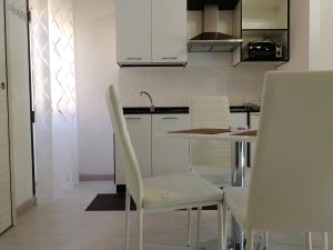 una cucina con armadi bianchi, tavolo e sedie di Tropea Travel's House a Tropea