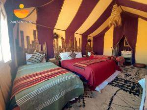 two beds in a room with purple and yellow walls at Arena y Sol Merzouga Camp in Merzouga