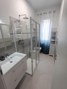 La salle de bains blanche est pourvue d'une douche et d'un lavabo. dans l'établissement Casa Vacanze Il Divano Rosso, à Foligno