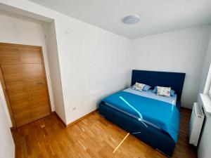 帕萊的住宿－Apartman Pale Jahorina，一间卧室设有蓝色的床,铺有木地板。