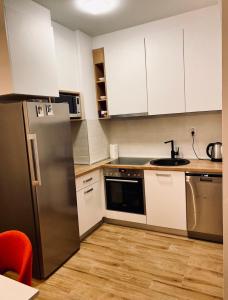 a kitchen with white cabinets and a stainless steel refrigerator at Apartman Pale Jahorina in Pale