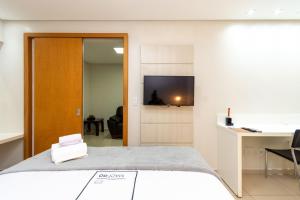 um quarto com uma cama, uma secretária e uma televisão em Conforto e Praticidade no Alto da Glória ESP2906 em Goiânia
