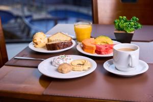 a table with plates of breakfast foods and a cup of coffee at Foz Plaza Hotel in Foz do Iguaçu