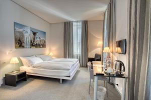 a hotel room with a white bed and a desk at Hôtel Au Terminus in Sierre